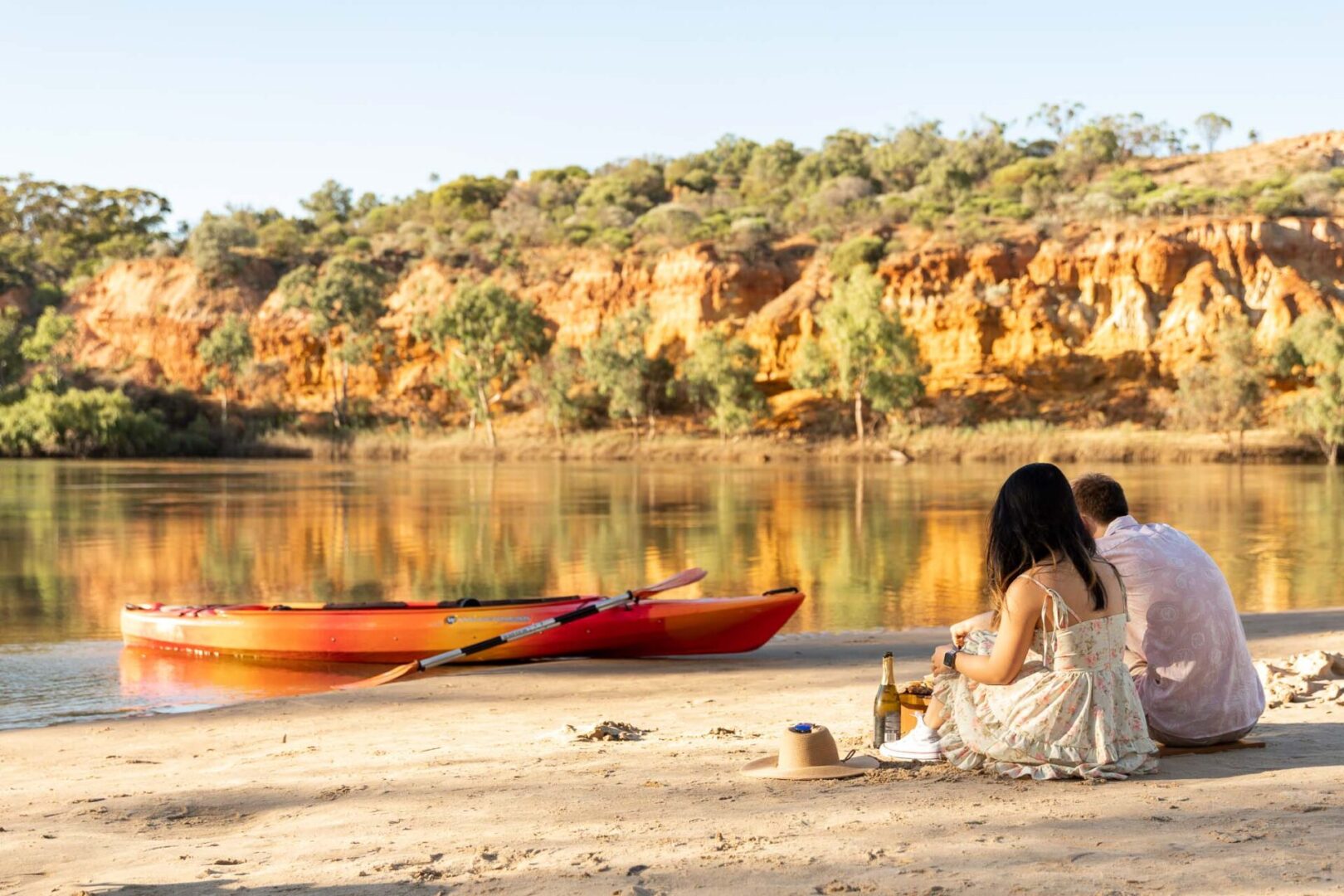 Young couple having a romantic breakfast on a sandbar next to a river.