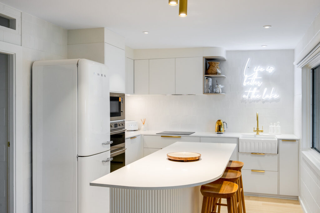 Photo of a newly renovated kitchen. White cabinets with gold handles.